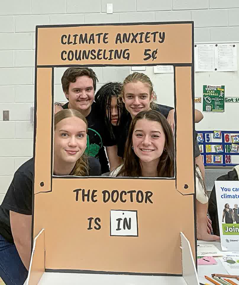 High school students posing behind a Climate Anxiety Counseling booth