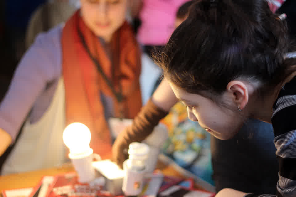 Participants examining illuminated bulbs during an energy demonstration