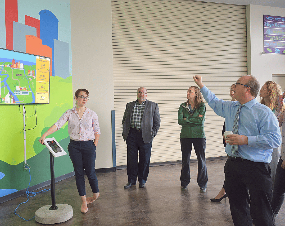 A group discussing the dashboard display and touch-screen exhibit at the Great Lakes Science Center