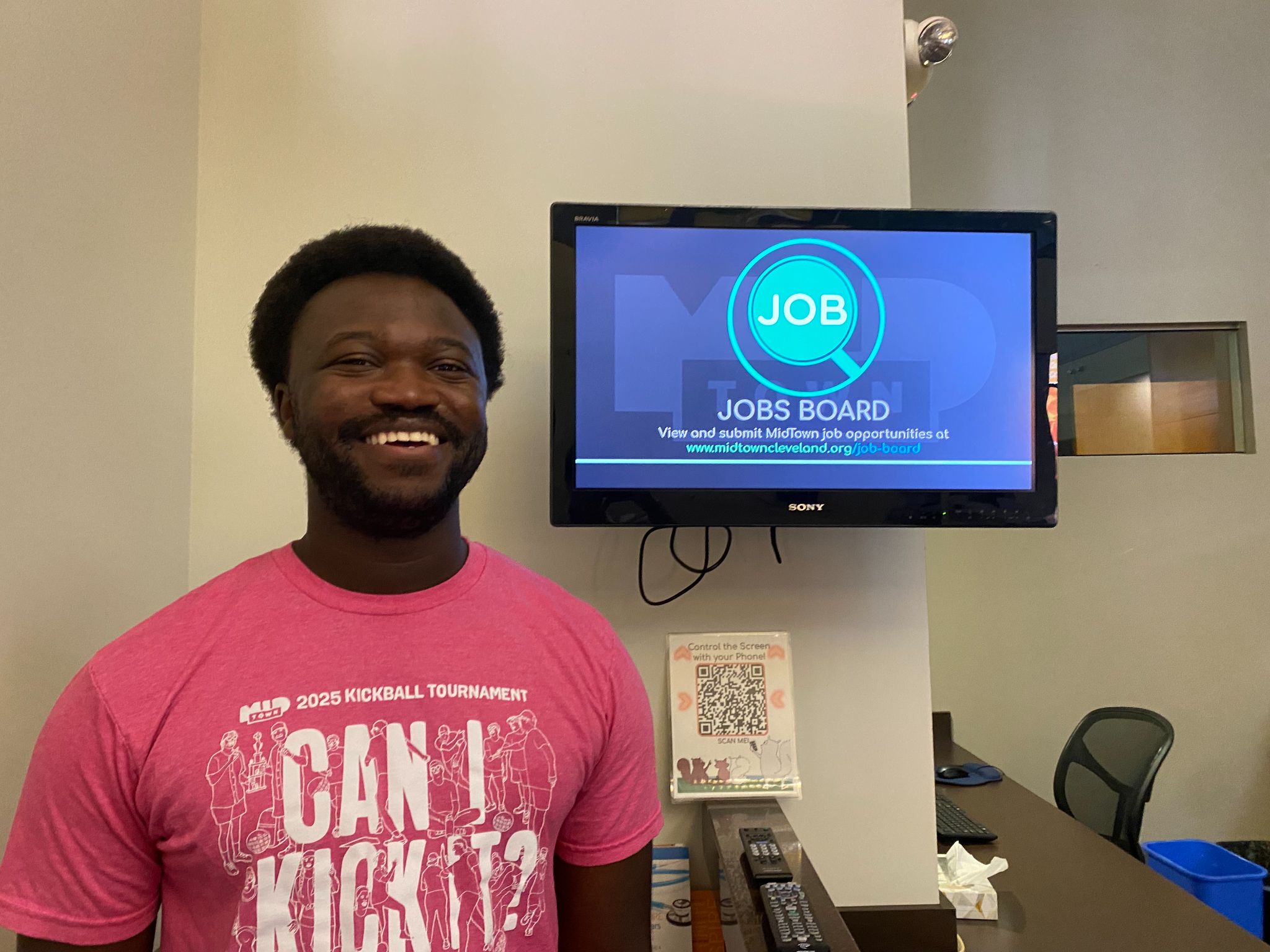 A person beside a digital sign displaying the MidTown jobs board at MidTown, Inc.